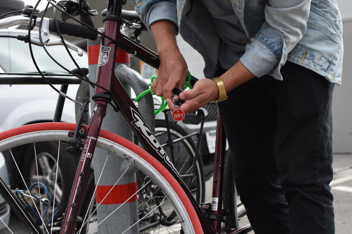 a Man uplocks a bike with a red front tire belonging to company Mibike, the bike has a red front tire.